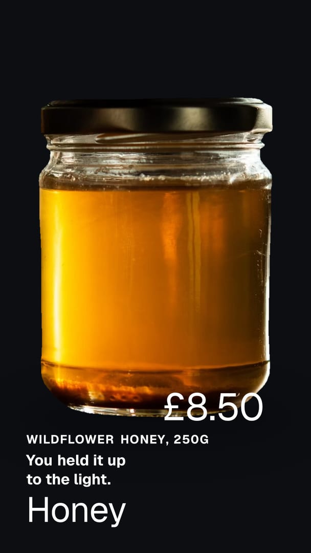 Ad for a preserving kitchen: a glass jar of golden honey with a black lid, lit from behind so the honey glows against a black background. The words on the picture read Wildflower honey, 250g, You held it up to the light, Honey, £8.50.