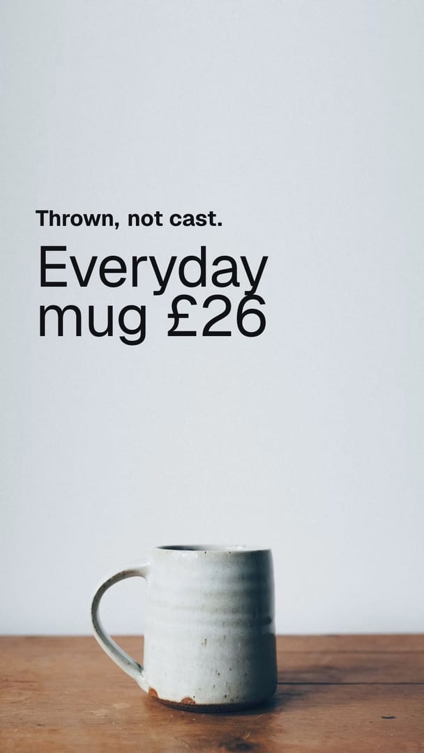 Ad for a pottery studio: a single hand-thrown stoneware mug with a pale speckled glaze and a bare clay foot, standing on a wooden table against a plain grey wall. The words on the picture read Thrown, not cast, Everyday mug £26.
